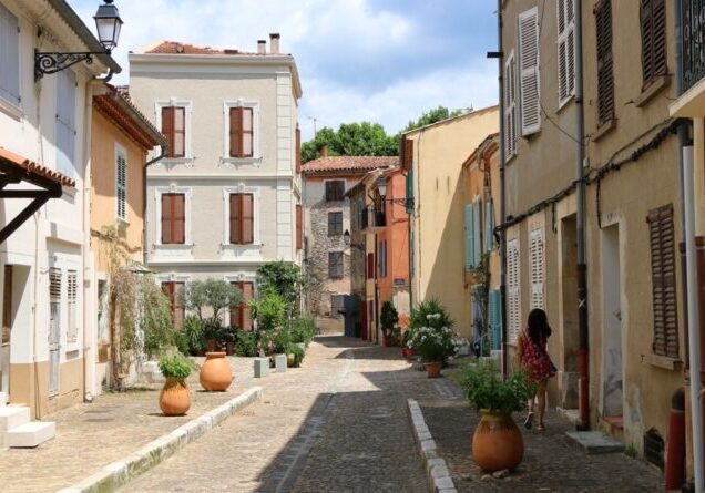 Collobrières, French. A woman walks in a typical street of the city center of the French old town.