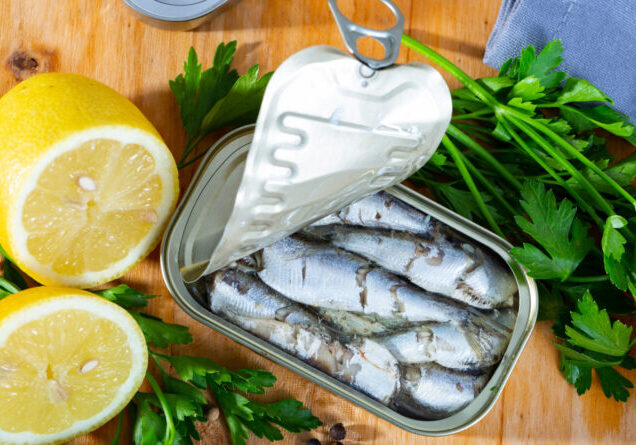 Open can of sardines preserves in oil on wooden table
