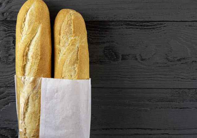 French bread mini baguette in a paper bag on a black wooden tabl