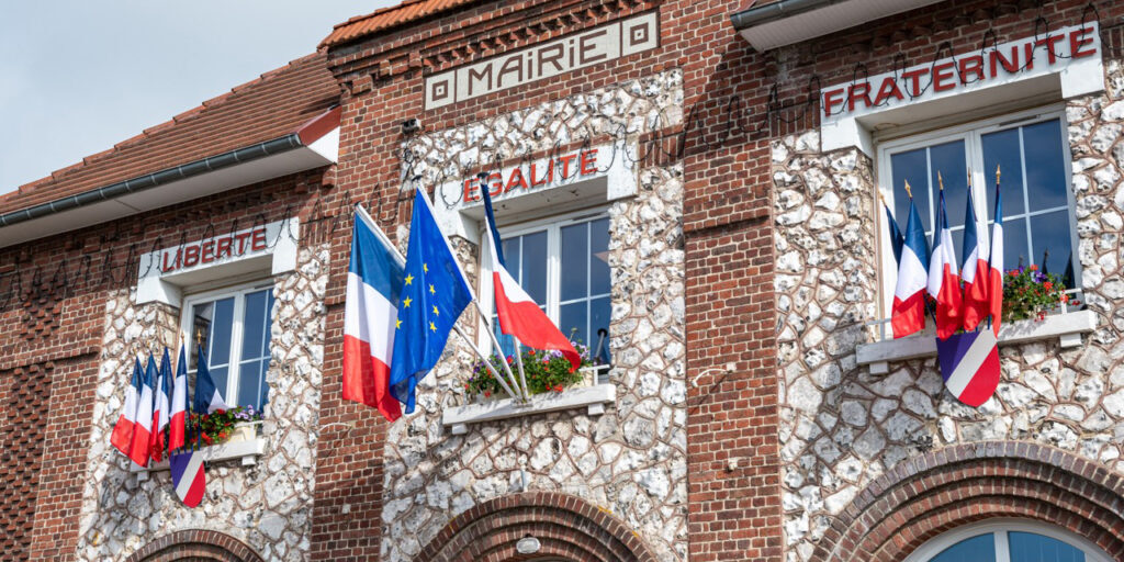 Facade d'une mairie avec drapeaux français  bleu blanc rouge et européen, à l'occasion de la  fête nationale du 14 juillet. Devise sur la facade : Liberté, Egalité, Fraternité
