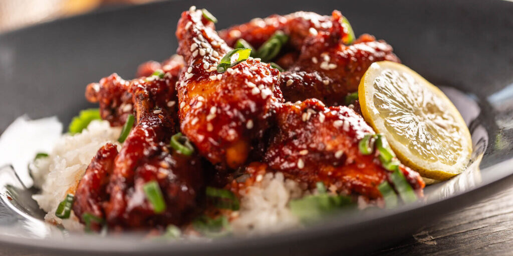 Marinated glazed sticky chicken thighs with seesame served with rice and coriander.