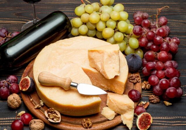 Whole round Head parmesan cheese, wine and grapeson wooden cutting board