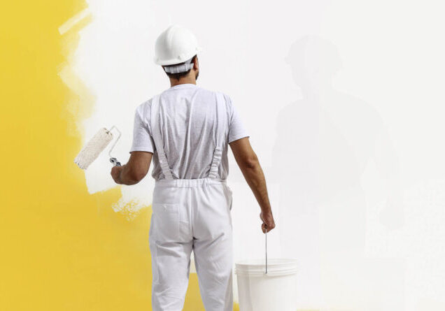 Rear view of painter man painting the wall, with paint roller and bucket, isolated on big empty copy space template