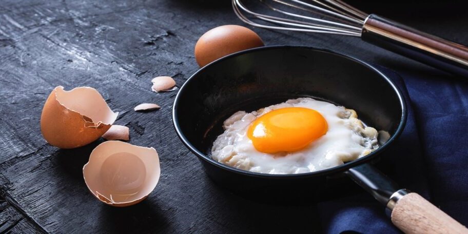 Menu cooking in kitchen egg fried egg in the pan  and fresh raw eggs  on black wooden background