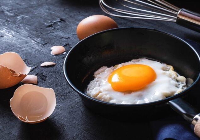 Menu cooking in kitchen egg fried egg in the pan  and fresh raw eggs  on black wooden background