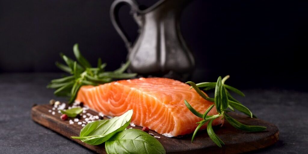 Salmon fish  with fresh basil and rosemary.  Steak on black background.